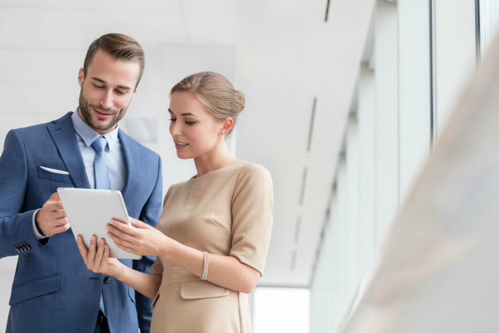 Professional environment. Male and female coworkers reviewing information on handheld tablet device.